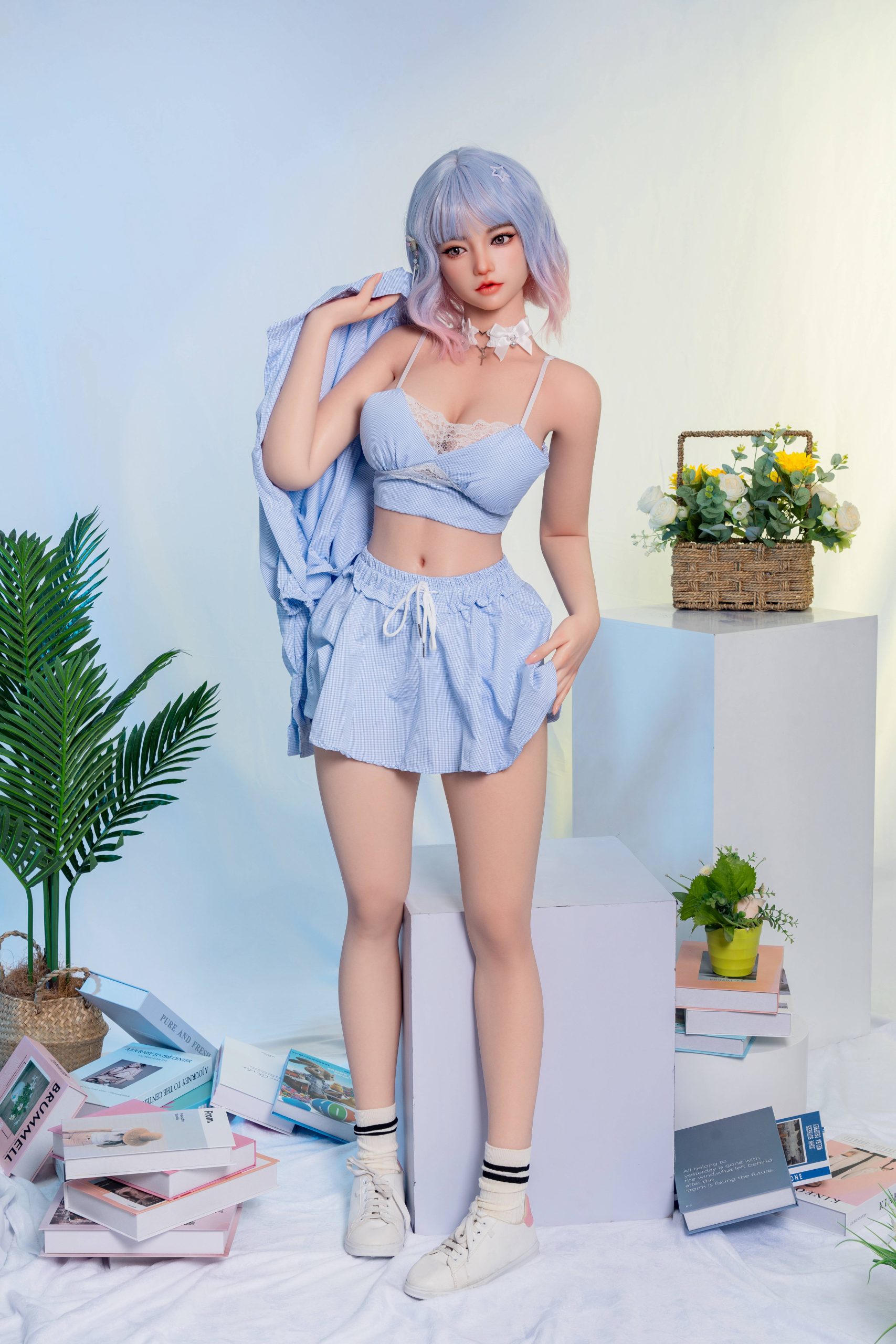 Silicone doll with pastel blue-and-pink bob hair wearing a light-blue outfit and white trainers