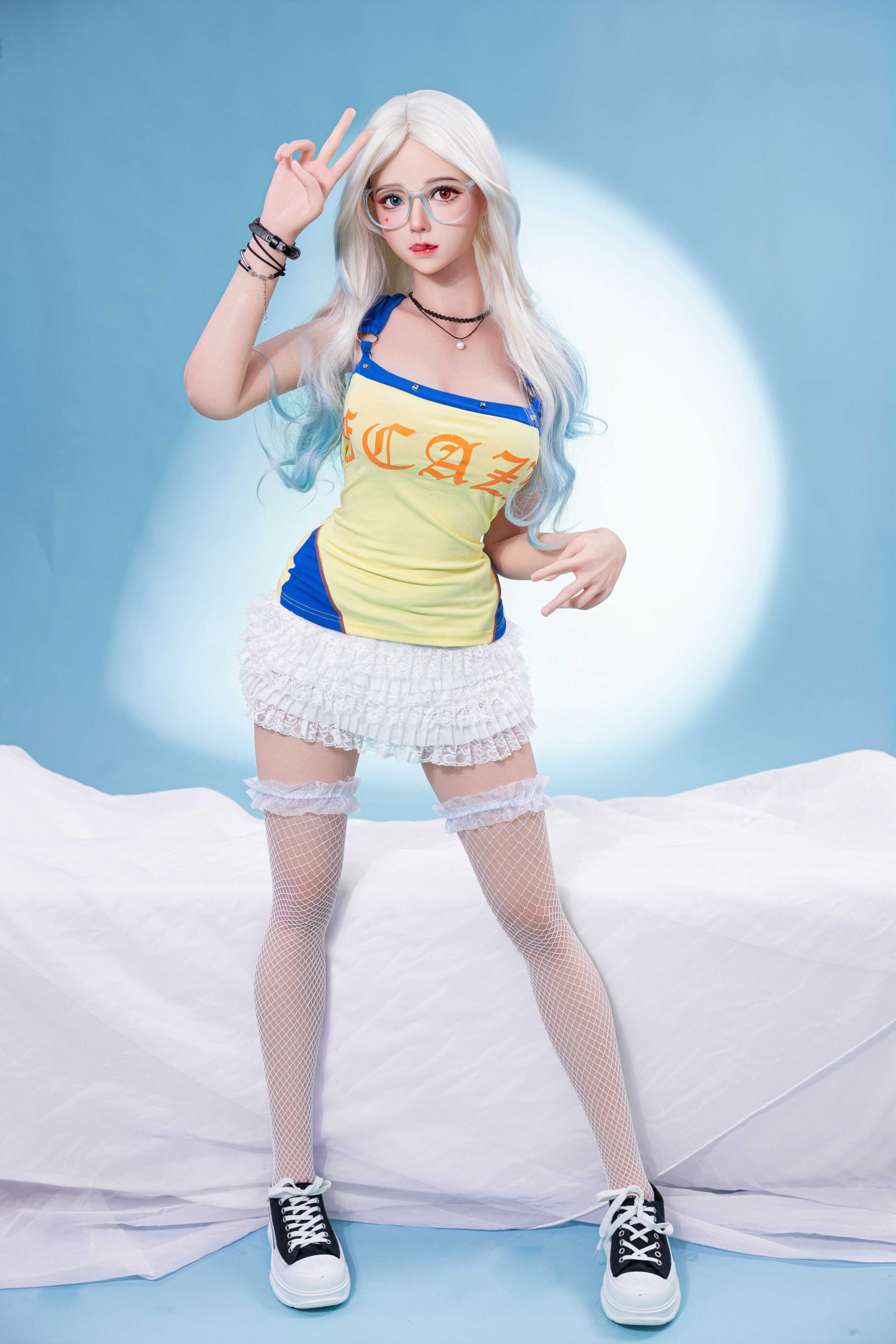 Silicone doll with white-blue hair seated in a yellow-and-blue outfit, white fishnet stockings and black trainers