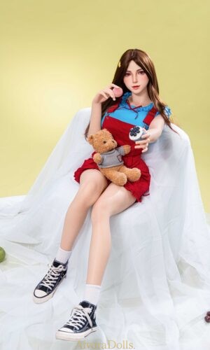 Silicone doll with brown hair and red eyes wearing a red pinafore-style outfit, blue top and black high-top trainers